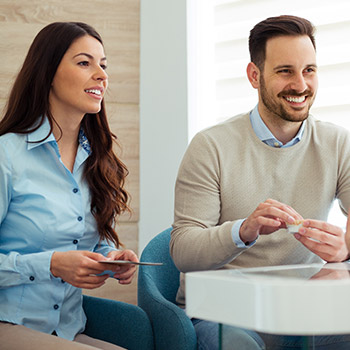 Smiling young man and woman checking in at dental office