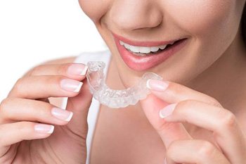 A woman preparing to insert an Invisalign aligner