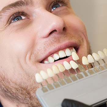 Man's smile compared with tooth color chart