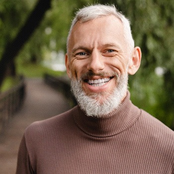 Senior man standing on bridge and smiling