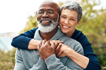 Senior man being hugged by senior woman from behind