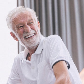 Senior man sitting on couch and smiling