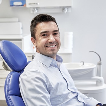Man in button-up shirt smiling in dental chair