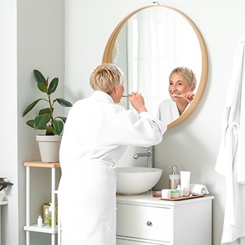 Woman in bathrobe brushing her teeth