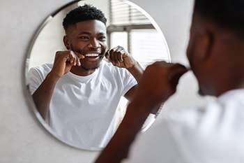 Man smiling while flossing teeth