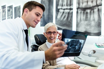 An older man smiling at a dental employee.