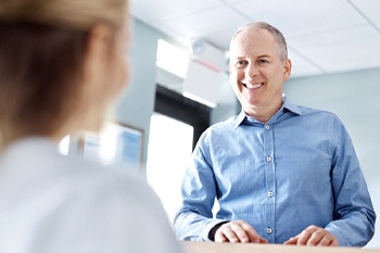 An older man smiling at a dental employee.