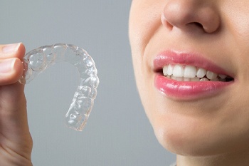 A woman holding an Invisalign aligner