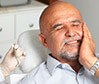 Man in dental chair holding jaw