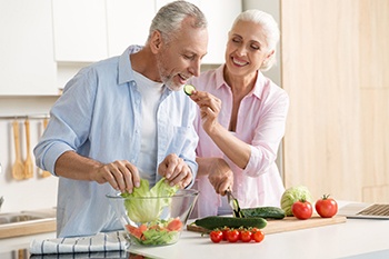Older couple preparing a salad together.