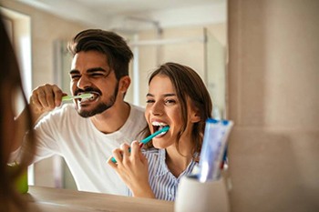 A couple brushing their teeth together