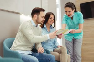 a couple looking at a brochure alongside a dental hygienist