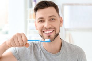 Man in grey shirt brushing his teeth