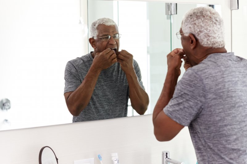 Man flossing as recommended by his dentist in Portage