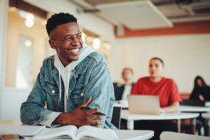 smiling teenage boy sitting at a classroom desk 
