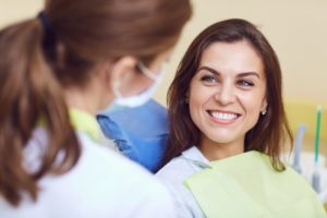 a woman smiling and speaking with her dentist during a checkup