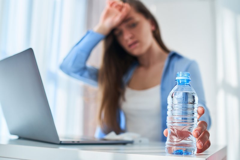 Thirsty woman reaches for water bottle.