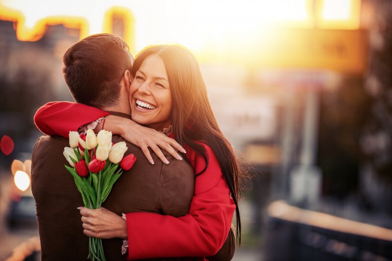 A smiling woman hugging a man while outdoors