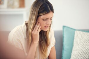 Young woman clutching her jaw in pain.