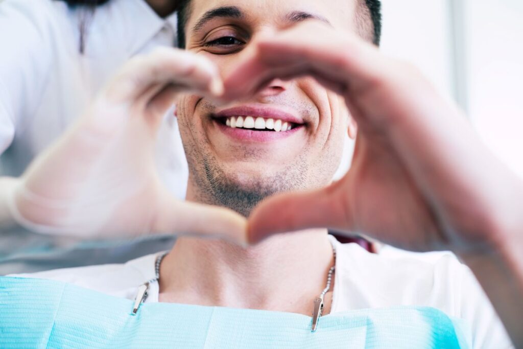 A smiling man making a heart with his hands